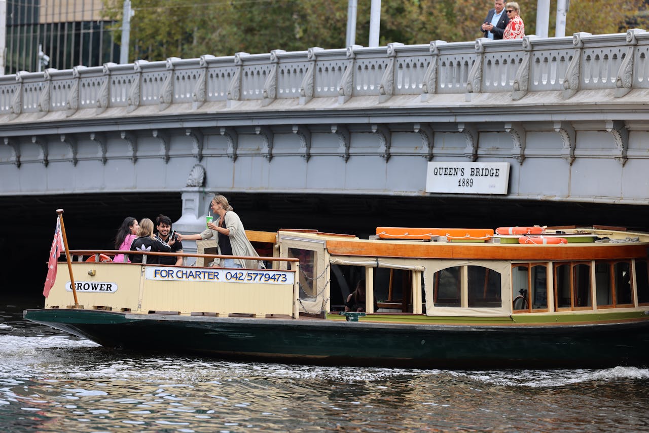 Tourists enjoying a chartered boat ride under Queen's Bridge in Melbourne.