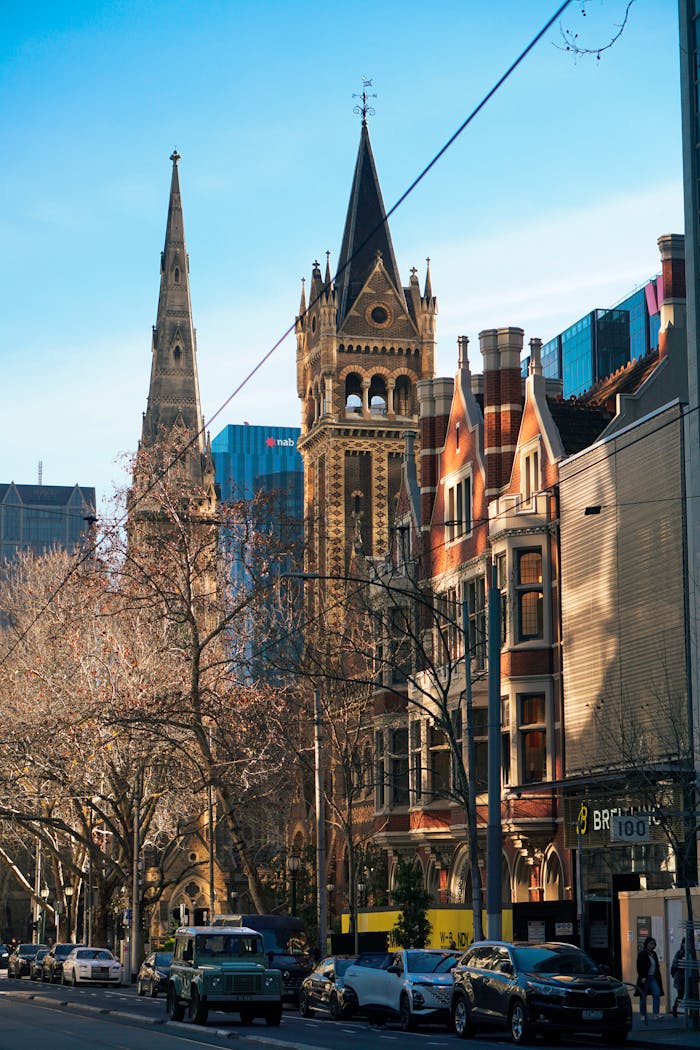 gallery-1 A blend of historic and modern architecture in Melbourne, showcasing iconic towers under a bright sky.