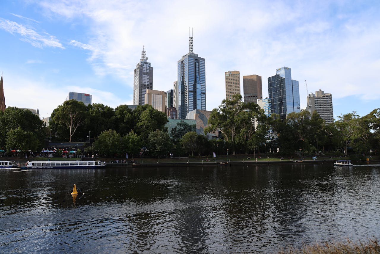 Skyline of Melbourne featuring skyscrapers along the Yarra River on a sunny day.